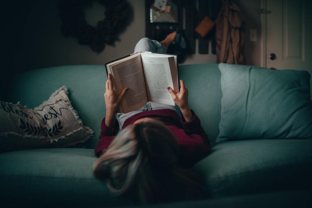 woman laying on a couch reading a book